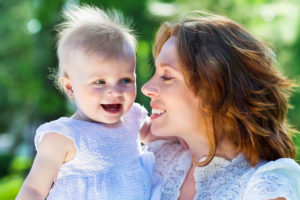 Beautiful Mother And Baby outdoors. Happy mum and her Child playing in Park together. Outdoor Portrait of happy family